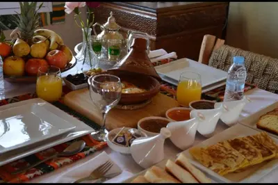 a table with food and glasses of orange juice at Chegaga Infinite Dunes Luxury Desert Camp in Mhamid