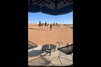 a group of people riding camels in the desert at Chegaga Infinite Dunes Luxury Desert Camp in Mhamid