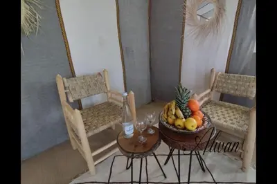 a table with a bowl of fruit and two chairs at Chegaga Infinite Dunes Luxury Desert Camp in Mhamid