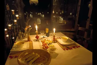 a table with two plates of food and two candles at Chegaga Infinite Dunes Luxury Desert Camp in Mhamid