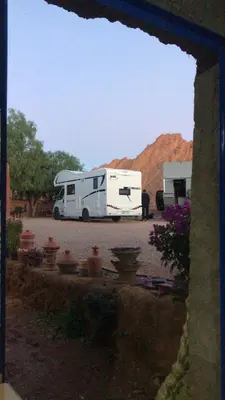 a white trailer parked in a parking lot with a mountain at Camping Restaurant Pattes des singes in Aït Ougliff