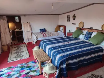 a bedroom with a large bed and a table and chairs at Luxury Desert Camp Erg Chegaga in El Gouera