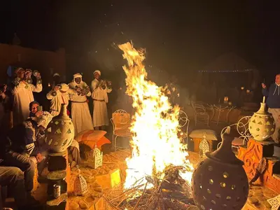 a group of people standing around a fire at Luxury Desert Camp Erg Chegaga in El Gouera