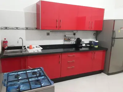 a kitchen with red cabinets and a sink and a refrigerator at grand apt climatisé et ensoleillé au centre de Fès in Fès