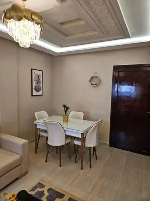 a dining room with a table and chairs and a chandelier at Joli appartement in Fès