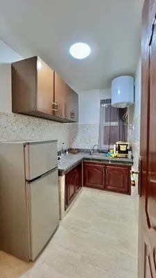 a kitchen with wooden cabinets and a stainless steel refrigerator at Joli appartement in Fès