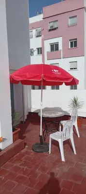 a red umbrella and a table and chairs on a balcony at Joli appartement in Fès