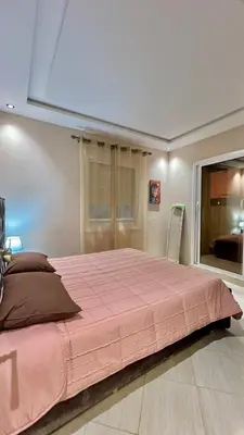 a bedroom with a large bed with a pink blanket at Joli appartement in Fès