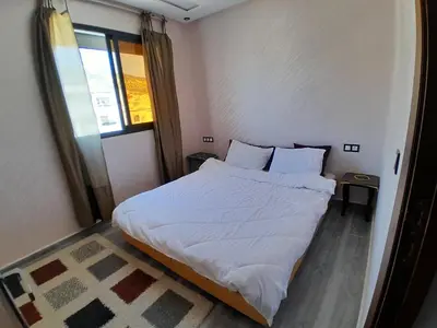 a small bedroom with a bed with white sheets and pillows at Apartment Oued Fes close to Euromed in Fès