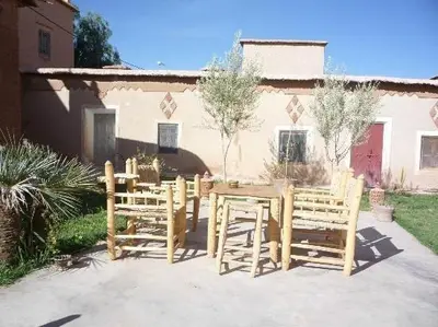 a group of wooden chairs and a table in a yard at kasbah De Alami hdida commune de ait ouassif kelaa mgouna tinghir in Kalaat MGouna