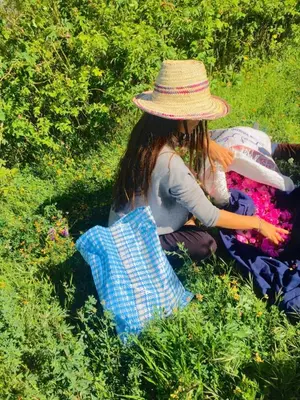a woman in a straw hat sitting in the grass at kasbah De Alami hdida commune de ait ouassif kelaa mgouna tinghir in Kalaat MGouna