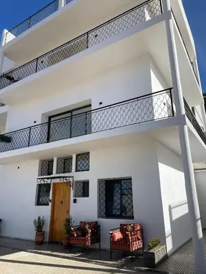 a white building with a balcony with red chairs at Appartement Fatima in Azrou