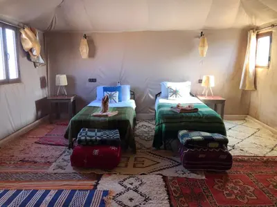 a room with two beds and luggage in a tent at Morocco Stars Camp in Hassilabied