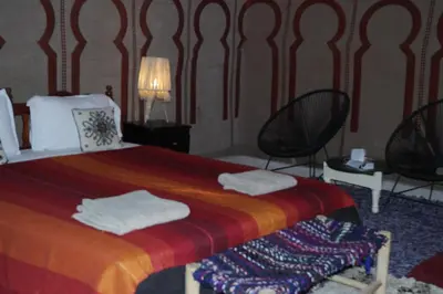 a bedroom with a bed with two black chairs at Morocco Stars Camp in Hassilabied