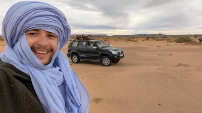 a man standing in the desert with a truck in the desert at Sahara binich sercices in Merzouga