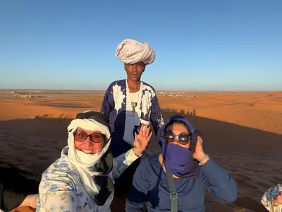 a group of three people standing in the desert at Sahara binich sercices in Merzouga
