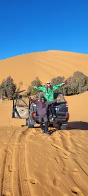a man sitting on the back of a car in the desert at Sahara binich sercices in Merzouga
