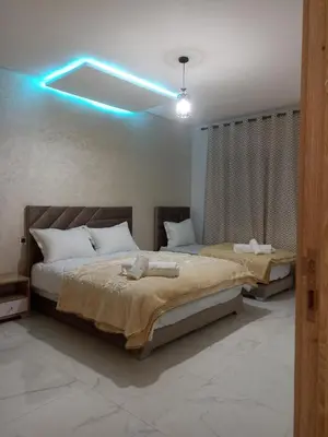 two beds in a bedroom with a blue light at Golden Mirage in Fès