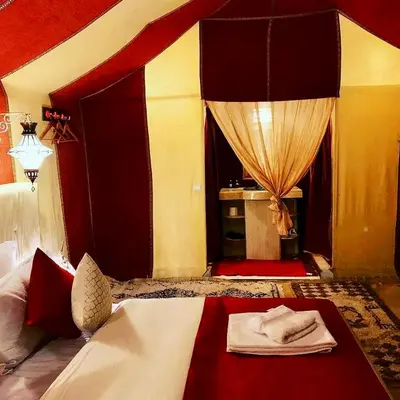a bedroom with a bed with red and yellow walls at Expérience Inoubliable dans une Tente de Luxe en plein Désert de Merzouga ! in Merzouga
