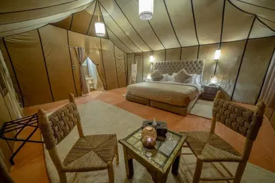 a bedroom with a bed and a table and chairs at Expérience Inoubliable dans une Tente de Luxe en plein Désert de Merzouga ! in Merzouga