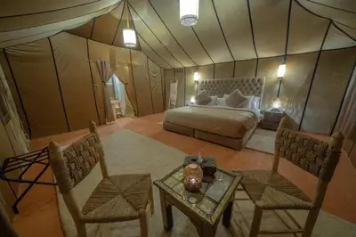 a bedroom with a bed and a table and chairs at Camp Luxueux en plein désert de Merzouga in Merzouga