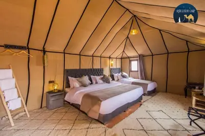 a bedroom with two beds in a tent at Camp Luxueux en plein désert de Merzouga in Merzouga