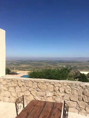 a wooden table and chairs on a stone wall at Dar El Mandar - Ferme & Table d'Hôte Berbère in Bhalil