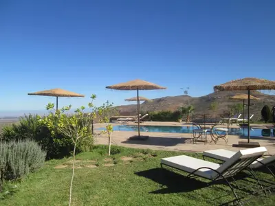 a pool with two chairs and umbrellas at Dar El Mandar - Ferme & Table d'Hôte Berbère in Bhalil