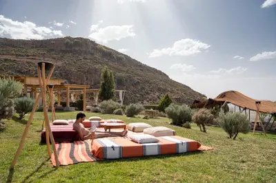 a man sitting on a bed in a field at Dar El Mandar - Ferme & Table d'Hôte Berbère in Bhalil