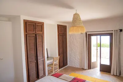 a bedroom with a bed and a table and a window at Dar El Mandar - Ferme & Table d'Hôte Berbère in Bhalil