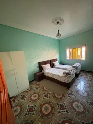 a bedroom with two beds and a rug at Résidence MARHABA in Ouarzazate