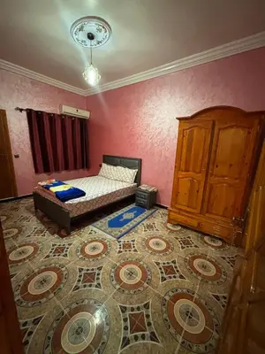 a bedroom with a bed and a cabinet and a rug at Résidence MARHABA in Ouarzazate