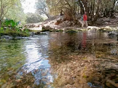 a man walking in the water near a stream at Zen environnement Horse riding in Zaouia dʼIfrane