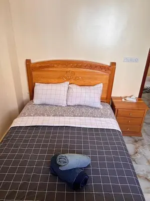 a bed with a wooden headboard and a pillow on it at Coquet F2 Jnane el Atlas Ifrane in Zaouia dʼIfrane