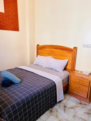 a bedroom with a bed and a wooden headboard and a dresser at Coquet F2 Jnane el Atlas Ifrane in Zaouia dʼIfrane