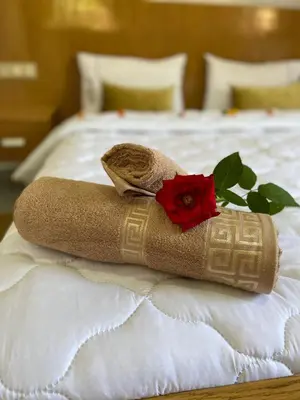 a rolled up towel with a red flower on a bed at charmante villa de luxe à Marrakech in Marrakech