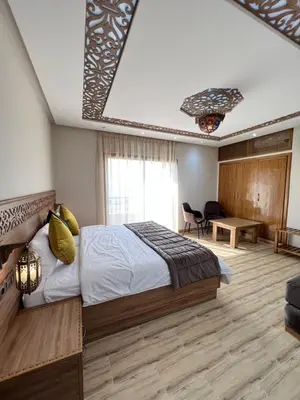 a bedroom with a bed and a living room at Ferme d'hôtes Bladna Garden in Meknès