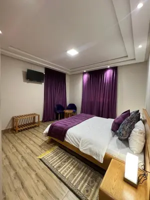 a bedroom with a large bed and purple curtains at Ferme d'hôtes Bladna Garden in Meknès
