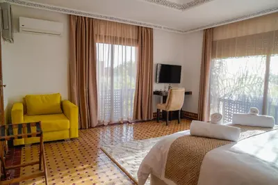 a hotel room with a bed and a yellow chair at Palais Volteras in Marrakech