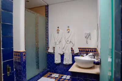 a bathroom with white robes hanging on a wall at Palais Volteras in Marrakech