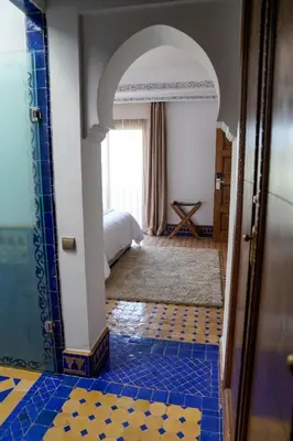 a bedroom with a bed and a blue tile floor at Palais Volteras in Marrakech