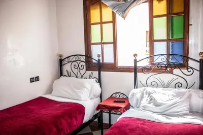 a bedroom with two beds and a window with stained glass at Hôtel Restaurant Ali in Midelt