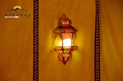 a lantern hanging on a wall with a sign at Sahara Luxury Camp - Nuit de rêve dans le désert de Merzouga ! in Merzouga