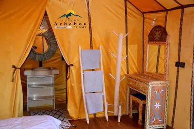 a tent with a table and a chair in it at Sahara Luxury Camp - Nuit de rêve dans le désert de Merzouga ! in Merzouga