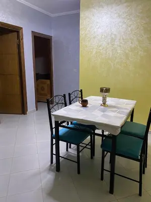 a dining room table with chairs and a white table at Appart propre et bien situé d in Fès
