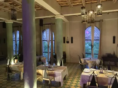 a room with white tables and chairs and windows at Kasbah Titrit & Spa in Aït Ben Haddou