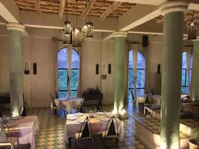 a dining room with tables and chairs and windows at Kasbah Titrit & Spa in Aït Ben Haddou