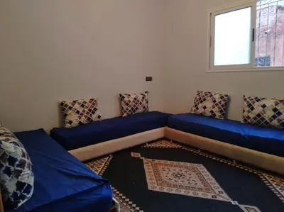 a living room with blue cushions and a window at Appartement centre ville de Tinghir in Tinerhir
