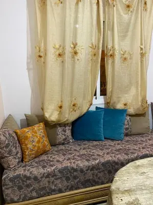 a couch with pillows sitting in front of a window at Appart propre et bien situé in Fès