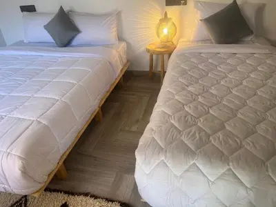 a bedroom with two beds and a table with a lamp at Rose Garden Dades in Kalaat MGouna